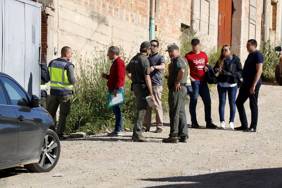 Agents de la policia espanyola amb Agents Rurals a la porta d'accés del magatzem de Bell-lloc d'Urgell on s'han detingut quatre persones | ACN