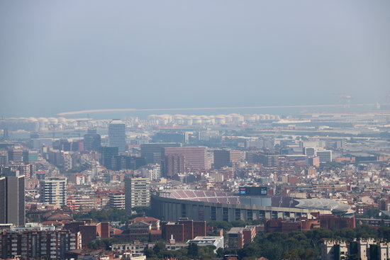 Barcelona amb el Camp Nou en primer pla i el port de fons amb boira per pol·lució al fons després que s'hagi declarat l'episodi per alta contaminació per partícules a Catalunya, l'1 de juliol del 2019 | ACN